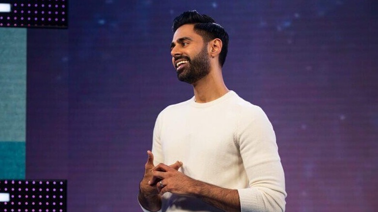 Hasan Minhaj smiles on a stage