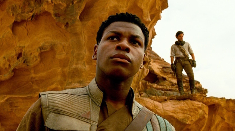 Finn on desert planet with Poe in the background