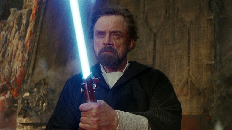 Luke Skywalker holds lightsaber on Crait