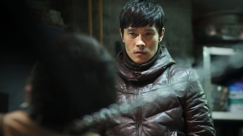 Kim Soo-hyeon looks at man strung up with phone cord in I Saw the Devil (2010)