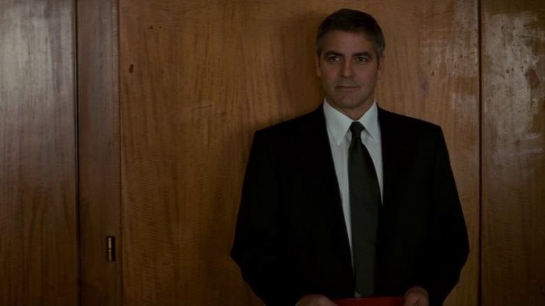 Michael Clayton standing against cabinet in office