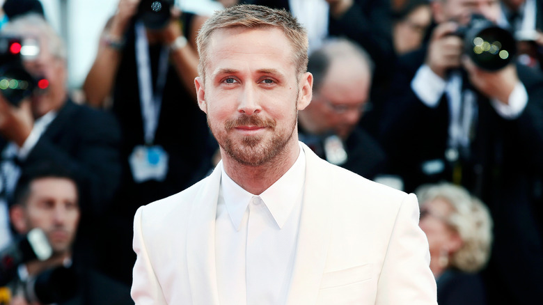 Ryan Gosling wearing a white suit posing for photographers