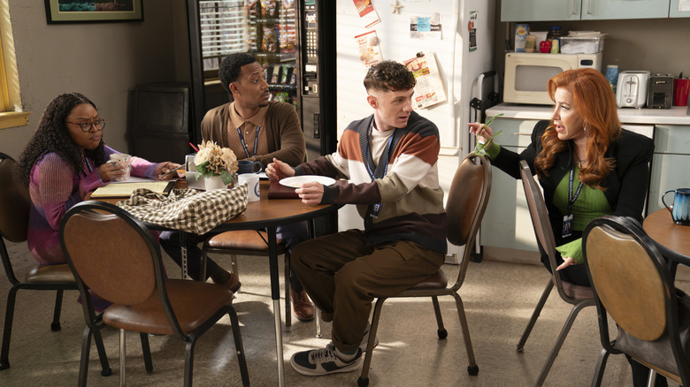 Janine, Gregory, Jacob, and Melissa talk while sitting at tables in the teacher's lounge