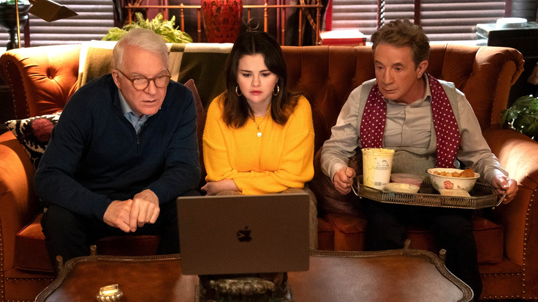 Charles, Mabel, and Oliver sit together on a couch and look at a laptop