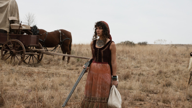 Noemi holding a rifle and a sack