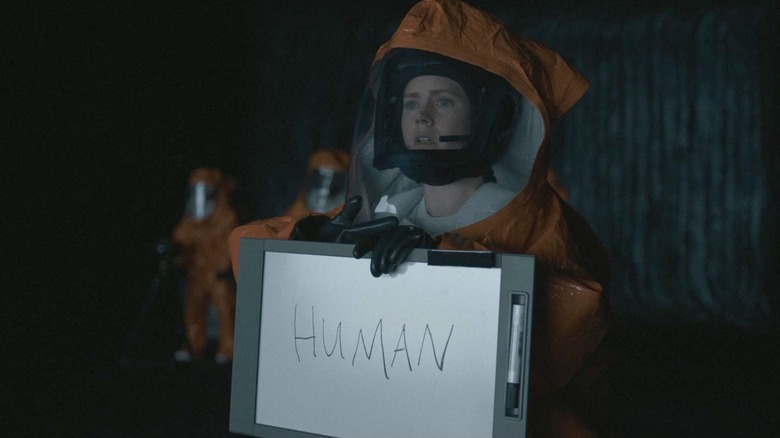 Amy Adams holds up a whiteboard that reads "human" in Arrival