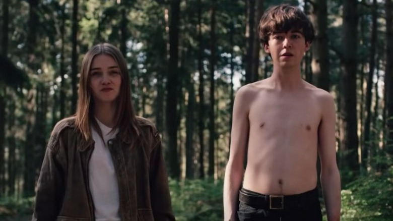 Shirtless James and Alyssa stand in forest