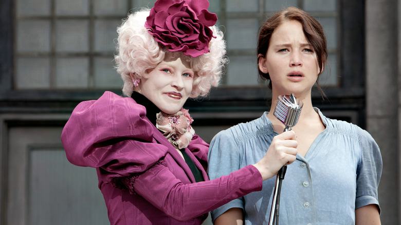 Effie holding Katniss' microphone