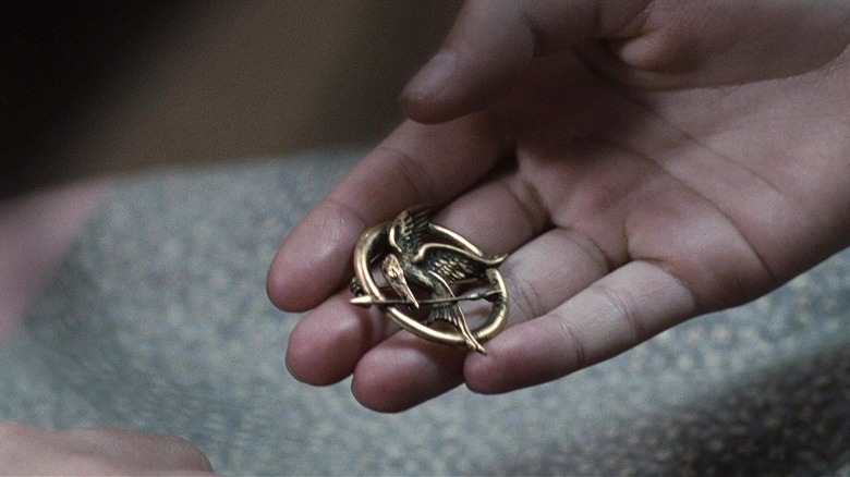 Hand holding Mockingjay pin