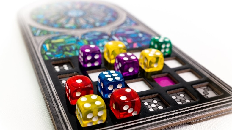 Translucent, colorful dice placed on stained-glass window pattern