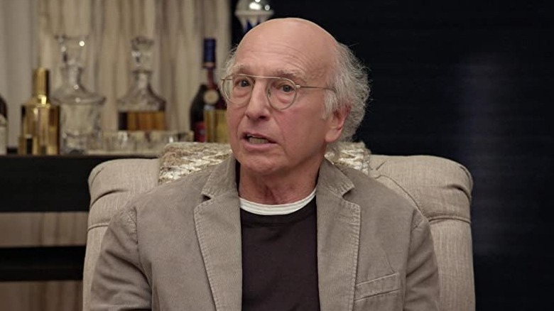 Larry David sits in chair