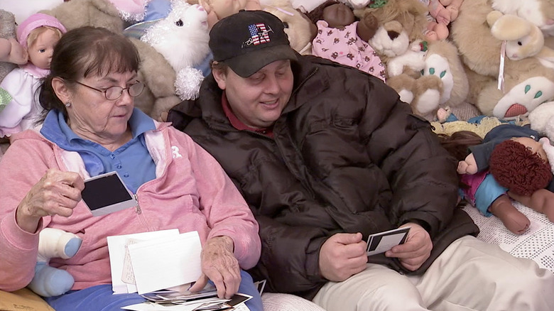 Phyllis and her son Bobby sit next to countless dolls