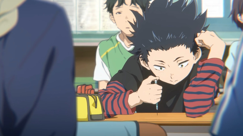 Young Shoya hunching over desk