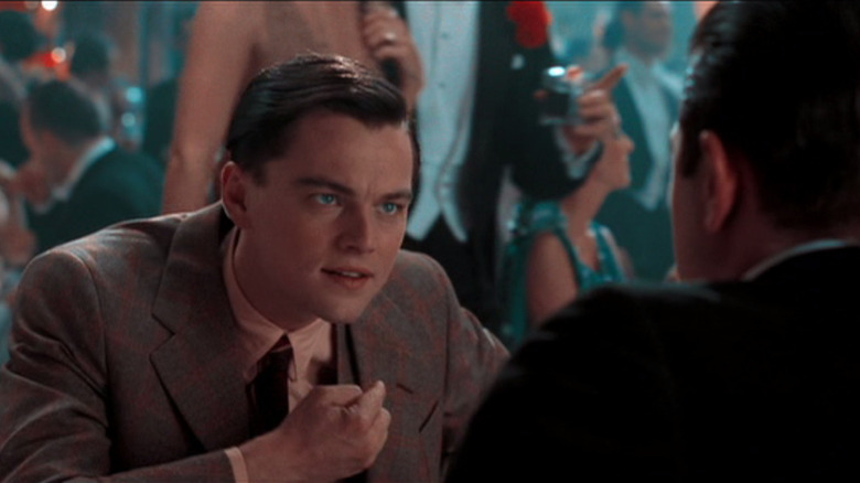 DiCaprio leaning forward to talk to someone in club