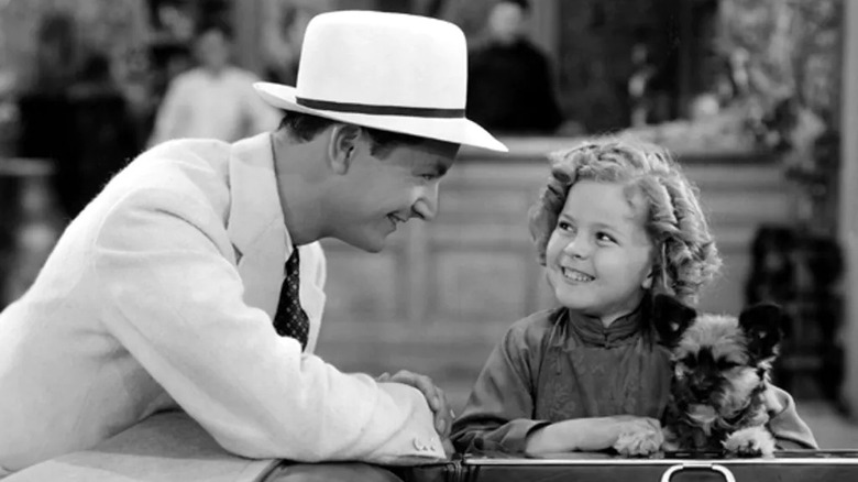 Shirley Temple smiles with a dog