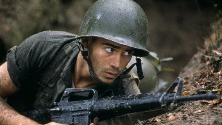 Colin Farrell on a hill with a rifle