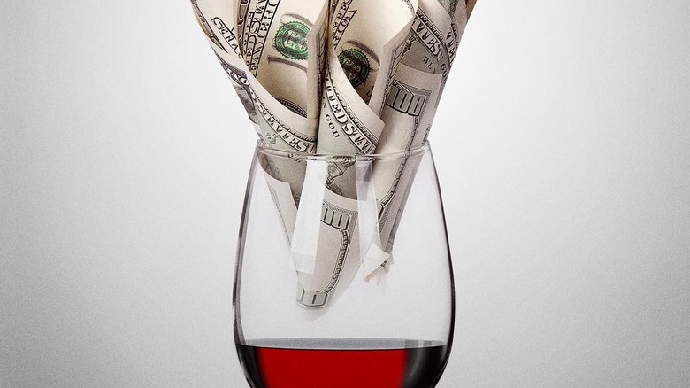 Hundred dollar bills in wine glass