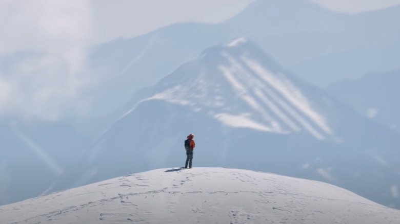 Alpinist stands on snowy mountain