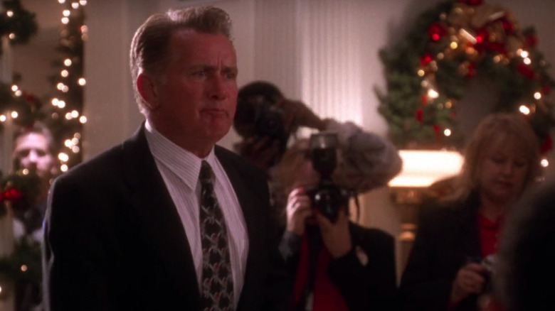 Bartlet standing in front of cameras and Christmas decorations 