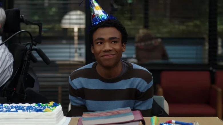 Troy Barnes smiles while wearing a birthday hat