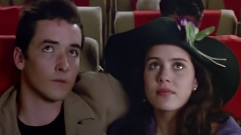 John Cusack and Ione Skye look up while sitting on airplane