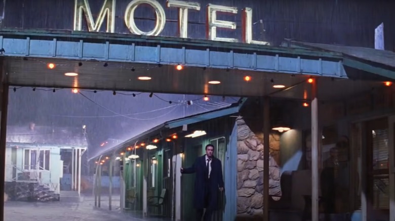 John Cusack standing under Motel sign