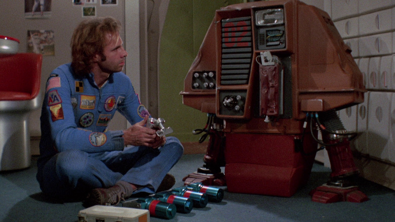 Bruce Dern sits with a robot