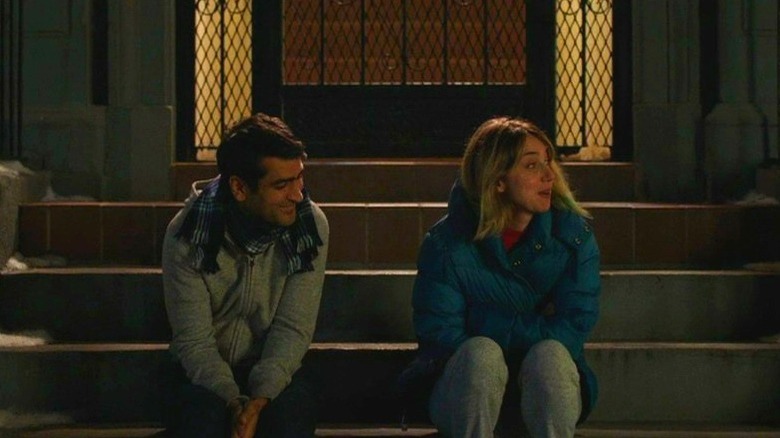 Kumail Nanjiani and Emily Gardner sit on steps