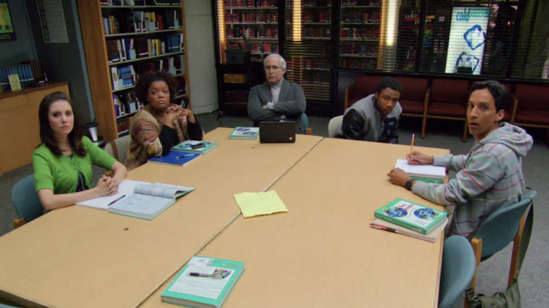 Gang sits at table in library