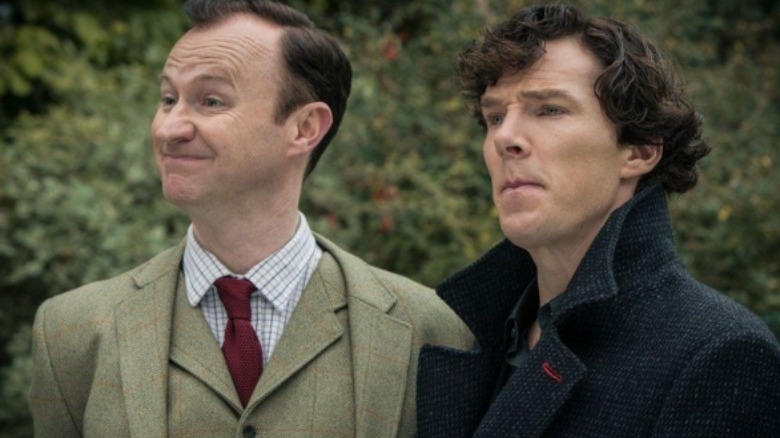 Sherlock looking skeptical and Mycroft smiling