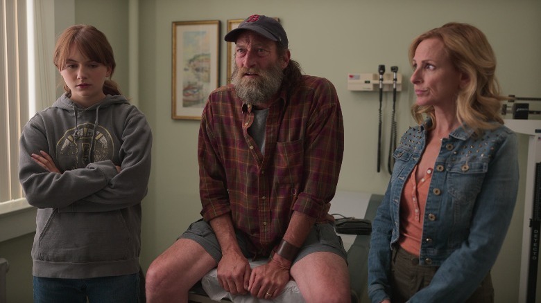 Frank sits on a doctor's exam table with his family around him