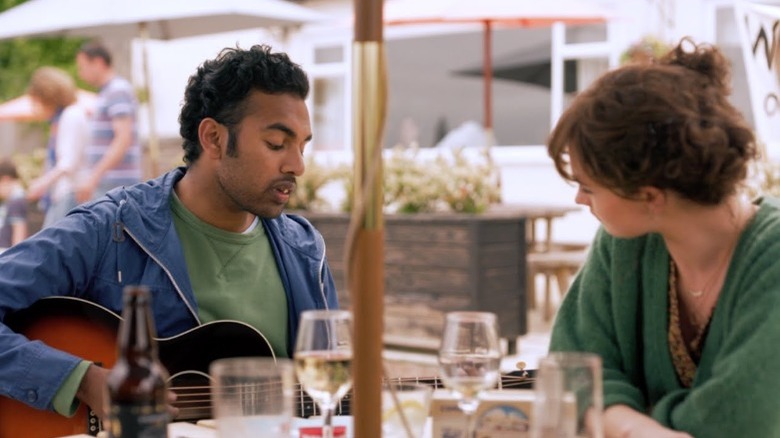 Jack playing the guitar for Ellie at an outdoor cafe