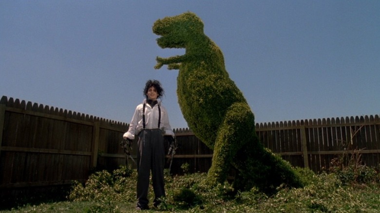 Edward standing by shrub sculpture