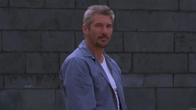 Richard Gere stands in front of gray wall