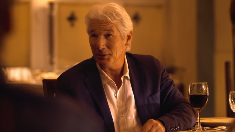 Richard Gere sits at a dinner table