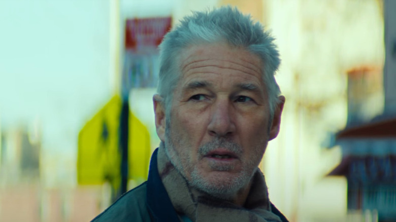 A scruffy Richard Gere stands on the street