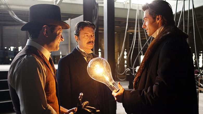 Three men surround a lightbulb