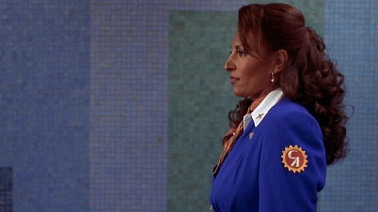 Side profile shot of Jackie Brown walking against blue tiled background.