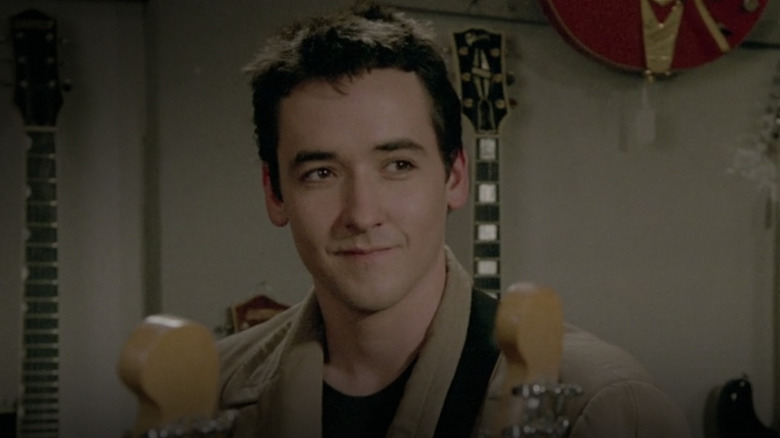 Lloyd Dobler smiling with guitars