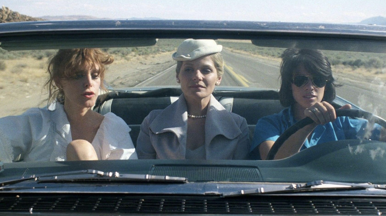 Three women drive through desert