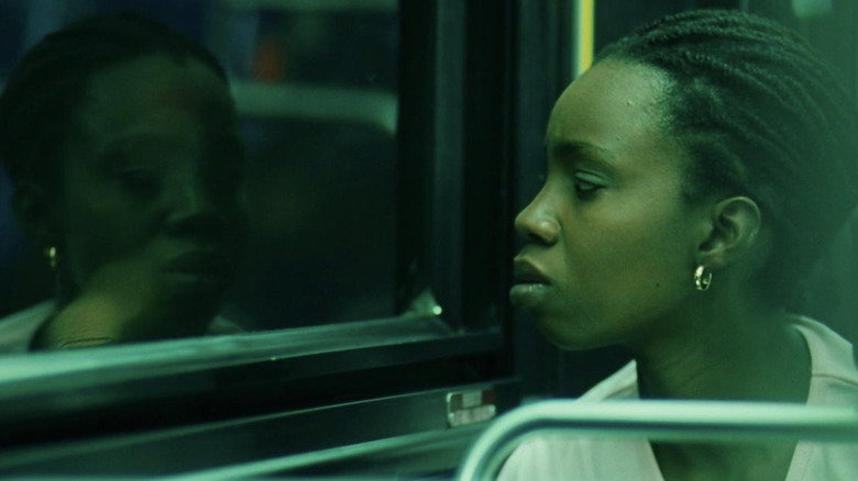 Lee looks at herself in bus window