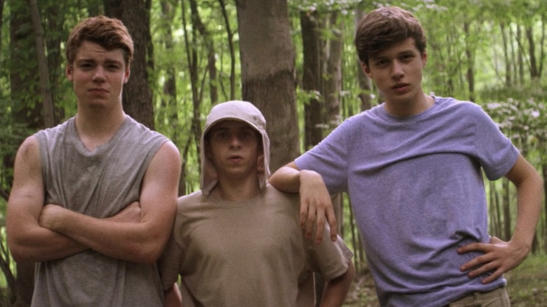 Three boys stare ahead in forest