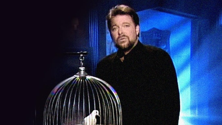 Jonathan Frakes standing behind a birdcage