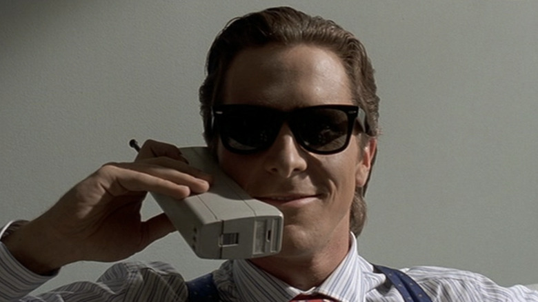 Christian Bale smiles with 90s cell phone to ear