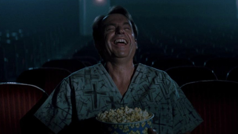 Sam Neill laughs alone in movie theater