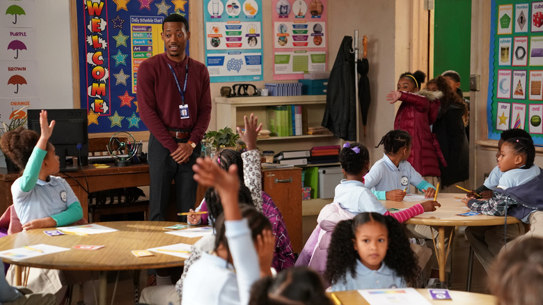 Gregory smiling at his class as the students raise their hands