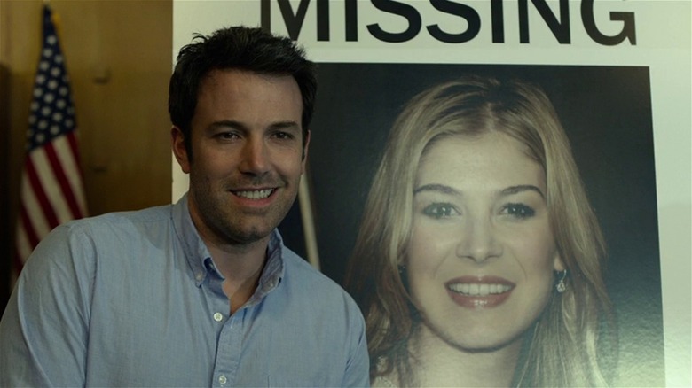 Nick Dunne smirking by missing poster