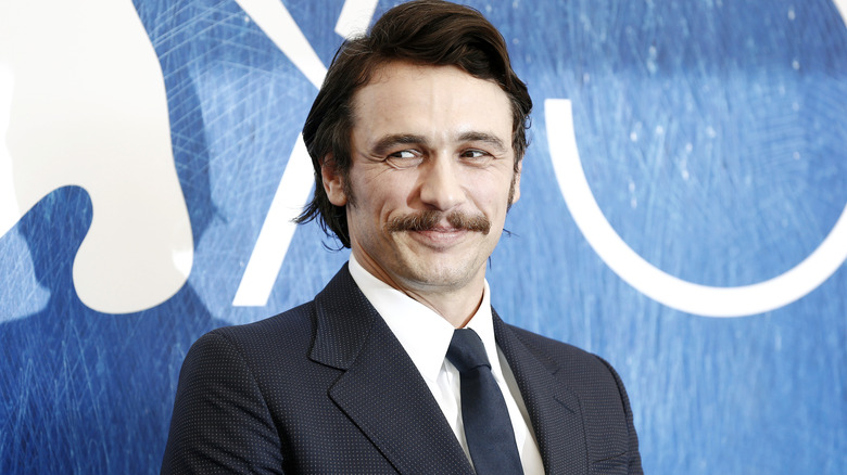 James Franco smirks and looks to the side