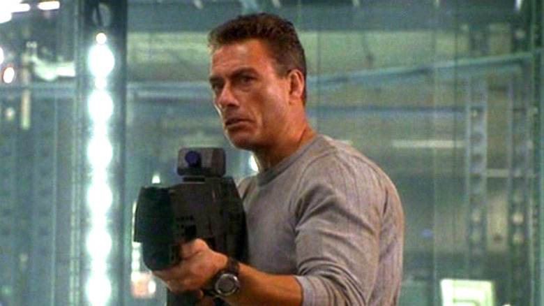 Jean-Claude Van Damme holds a gun