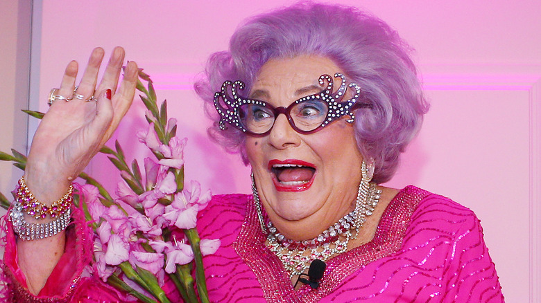 Dame Edna happy holding flowers